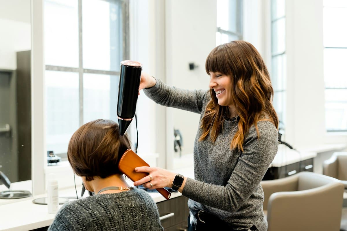 Coiffeuse mettant en forme les cheveux d'une cliente
