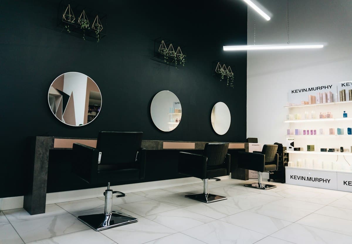 Intérieur du salon : fauteuils noirs face à des miroirs ronds